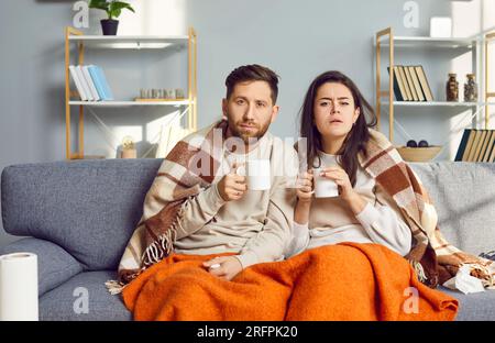 Couple relaxing on couch under blanket at home in living room Stock Photo
