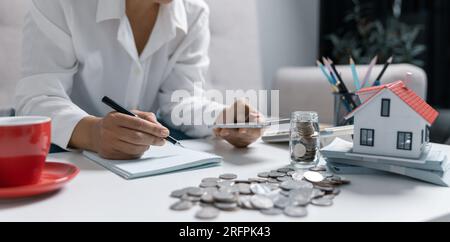 Concentrated Asian woman calculating expenditures, analyzing paper bank bills, managing monthly budget, planning investment, paying for service or uti Stock Photo