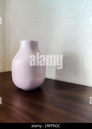 One modern empty pink ceramic vase on wooden table. Scandinavian interior, design, concept of minimalism. Empty wall. Copy space. Close-up. Selective Stock Photo