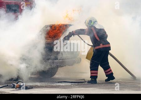 Firefighters attack a propane fire. Fireman Putting Out Fire. Firemen extinguishing a car fire. Stock Photo