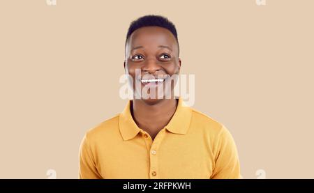 Portrait of happy funny african indian young man looking aside on beige background. Stock Photo