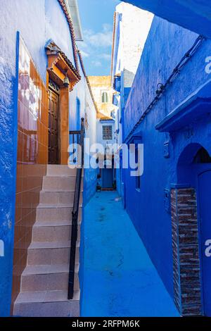Everything is blue, a narrow long passage with some tile reflecting it all and the blue sky Stock Photo