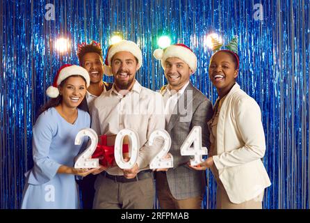 Portrait of cheerful young multiracial friends having fun together at 2024 New Year party. Stock Photo