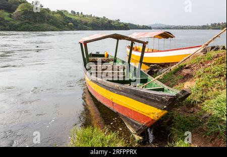 Two wooden boats, painted in bright colors, await tourists for an excursion on the nascent Nile. Jinja, Uganda. Stock Photo