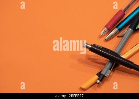 Different pencils isolated on an orange background with copyspace (aka empty text space) on the left. School background. Stock Photo