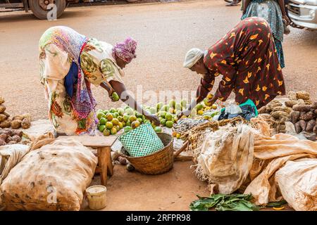 At the market in Jinja, Uganda, two women bend down to choose the fruits they are going to buy. Stock Photo