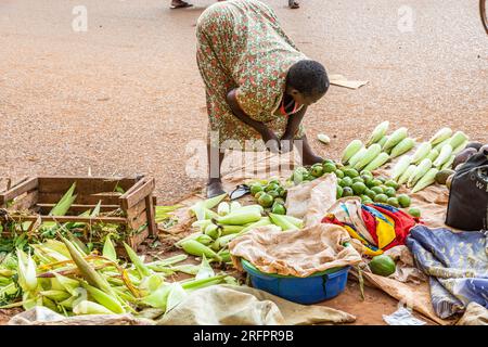 At the market in Jinja, Uganda, woman examining fruits and vegetables for sale. Stock Photo