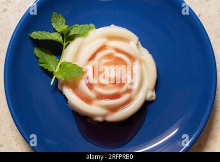 Panna cotta jelly with strawberry sauce and fresh mint on a plate Stock Photo