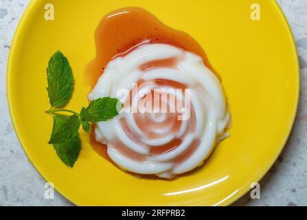 Panna cotta jelly with strawberry sauce and fresh mint on a plate Stock Photo