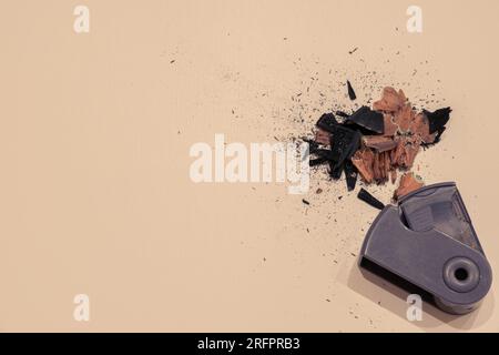 Pencil sharpener and a pile of pencil shavings isolated on a beige - white background with copyspace (aka empty text space). School background. Stock Photo
