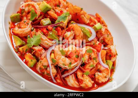 cocktail de camarones, mexican shrimp cocktail salad, chilled appetizer of shrimp, fresh tomato, pepper, avocado, red onion and cilantro in white bowl Stock Photo