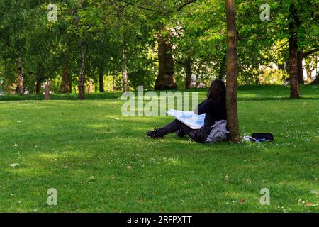 LONDON, GREAT  BRITAIN - MAY 12, 2014: An unidentified young woman draws in one of the city parks. Stock Photo