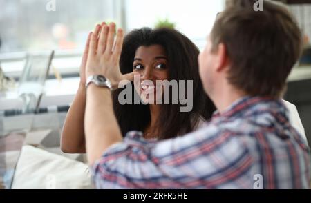 Portrait of man and woman giving high five and smiling. Wife looking at husband with happiness Stock Photo