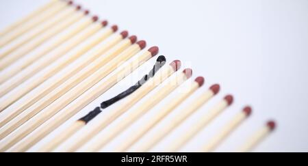 Close-up view of one wooden burnt match among many new whole. Stock Photo