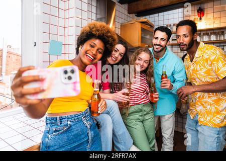 Multiethnic group of happy young friends having dinner barbecue party on rooftop at home - Multiracial cheerful young adult people having fun and bond Stock Photo