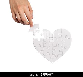 Completing heart shaped puzzle with missing lacking piece isolated on white background. Love problems solving concept. Stock Photo