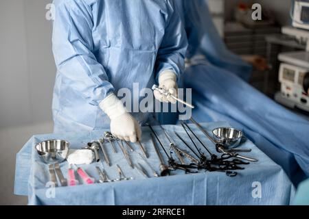 Setting Up Instruments Surgery Surgeon preparing surgical instruments on table, ready for medical ...