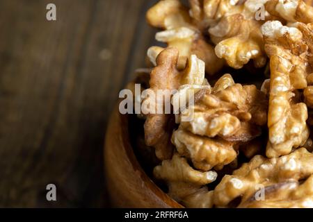 Peeled walnuts in a wooden bowl on the table, dry walnuts without shells Stock Photo