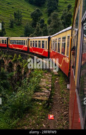 Himalayan Queen Toy train Kalka-Shimla route, moving on railway to the hill, among green natural forest. shimla, Himachal Pradesh, India Stock Photo