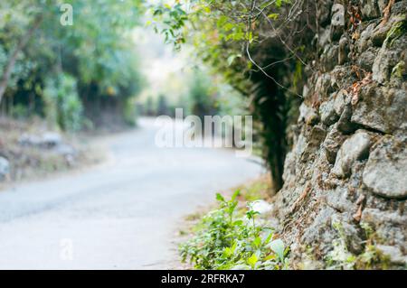 A beautiful asphalt road leading through with blur stone walls in the foreground. Diminishing Perspective. Travel Holiday backgrounds. Copy Space for Stock Photo