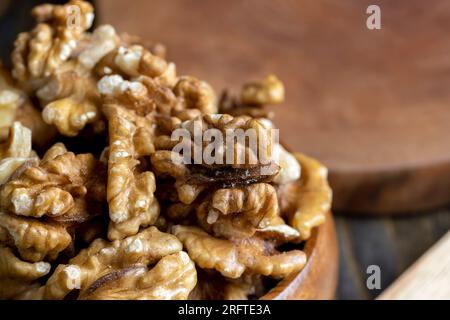 Peeled walnuts in a wooden bowl on the table, dry walnuts without shells Stock Photo
