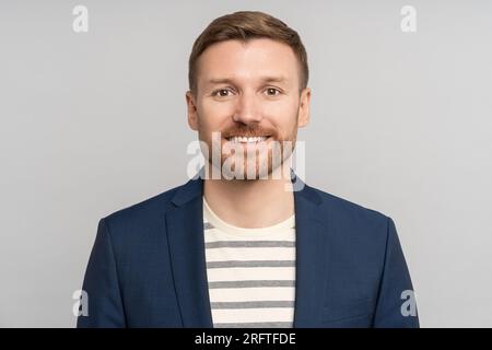 Confident entrepreneur man with positive emotion smiles standing on studio grey wall background  Stock Photo