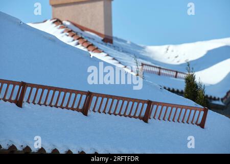 Snow guard for safety in winter on house roof top covered with ceramic shingles. Tiled covering of building Stock Photo