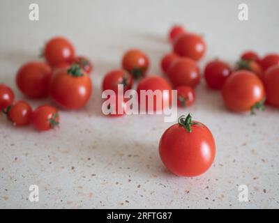 Red cherry tomatoes with pedicels on the table, selective focus. Harvest of small tomatoes Stock Photo