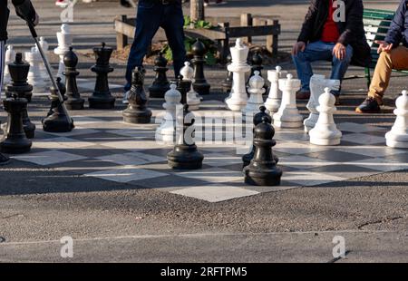 Group of people playing chess game on the giant chess board at the Parc des Bastions in Geneva, Switzerland. Stock Photo