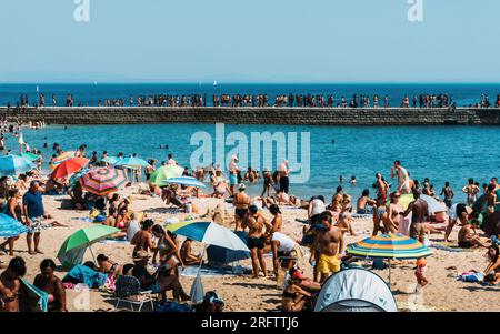 Estoril, Portugal - August 5, 2023: Crowded sandy Tamariz beach in Estoril near Lisbon, Portugal during the summer Stock Photo