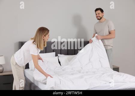 Couple changing bed linens in room. Domestic chores Stock Photo