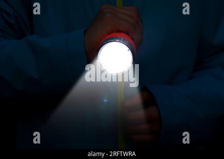 Man with bright flashlight in darkness, closeup Stock Photo
