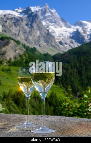 Drinking of dry white Roussette de Savoie and Vin de Savoie french wine from Savoy region with view on Hautes Alpes mountains with snow on tops Stock Photo
