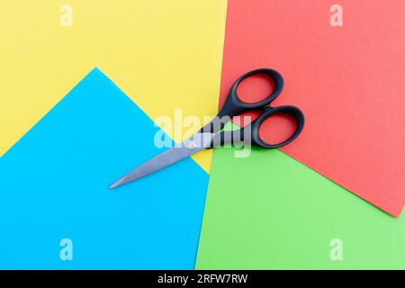 Scissors placed on colored papers, after some edits. Stock Photo