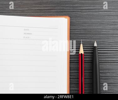 A pen, pencil and book placed on textured table. After some edits. Stock Photo