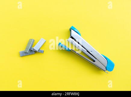 A stapler and its supplies isolated on yellow background, after some edits. Stock Photo