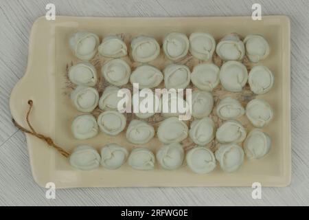 Homemade dumplings on board. Frozen semi-finished products. Preparations of homemade food. Stock Photo