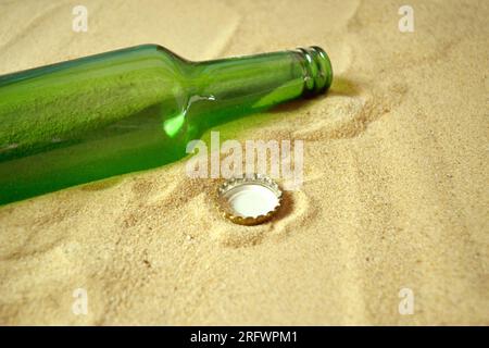 A waste of a bottle cap with a bottle thrown on the sand of the beach with copy space Stock Photo