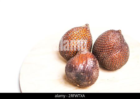 Salak or snake fruit in wooden plate isolated on white background. Stock Photo