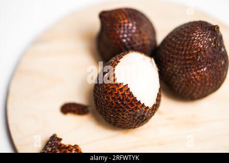 Salak or snake fruit in wooden plate isolated on white background. Stock Photo