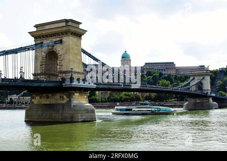 perspective view of the renovated Chain Bridge. tour boat on the Danube. The Buda Castle in background. reopening it to the public after construction Stock Photo