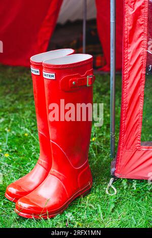 pair of red rain boots in front of tent Stock Photo