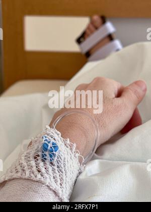 Caucasian woman lying in hospital with broken leg. IV solution drip on her hand. Medical concept. Stock Photo