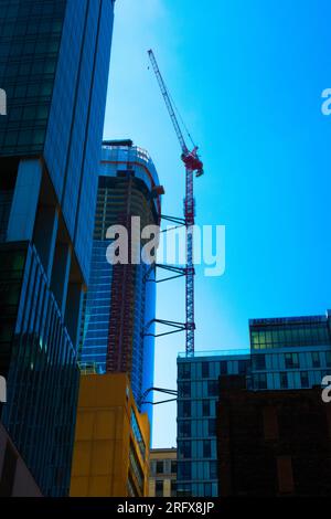 Majestic view of a red highrise crane operating against a bright blue sky. Shadows and reflections and striking perspective all add to the visual interest. Stock Photo