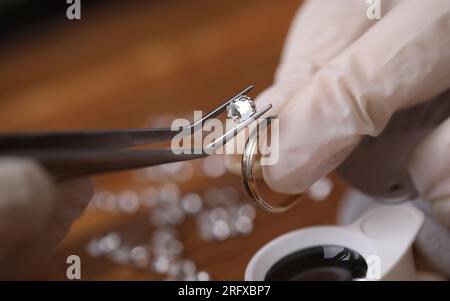 Close-up of goldsmith hand decorating precious ring with beautiful diamonds Stock Photo