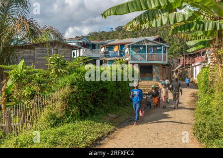 Andasibe, Madagascar - May 26.2023: People walking along the road in Andasibe, background wooden houses Stock Photo