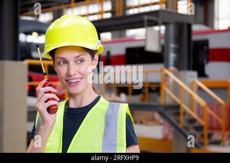Young caucasian engineer woman using radio for command with worker checking electric train for planning maintenance in station, transport and infrastr Stock Photo