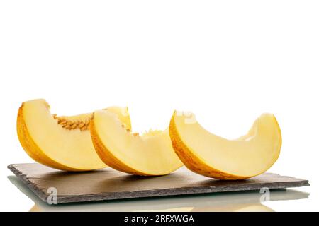 Three slices of yellow melon on slate stone, macro, isolated on white background. Stock Photo