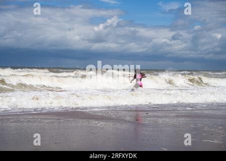 Kent UK. 06th August 2023. UK Weather. Strong  winds can be felt and choppy sea water seen at Kent south coast while Storm Antoni hits England' south west coast with near-80mph gusts. People still enjoying sunny day on beach swimming in incoming waves. Credit: xiu bao/Alamy Live News Stock Photo