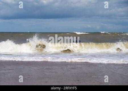 Kent UK. 06th August 2023. UK Weather. Strong  winds can be felt and choppy sea water seen at Kent south coast while Storm Antoni hits England' south west coast with near-80mph gusts. People still enjoying sunny day on beach swimming in incoming waves. Credit: xiu bao/Alamy Live News Stock Photo